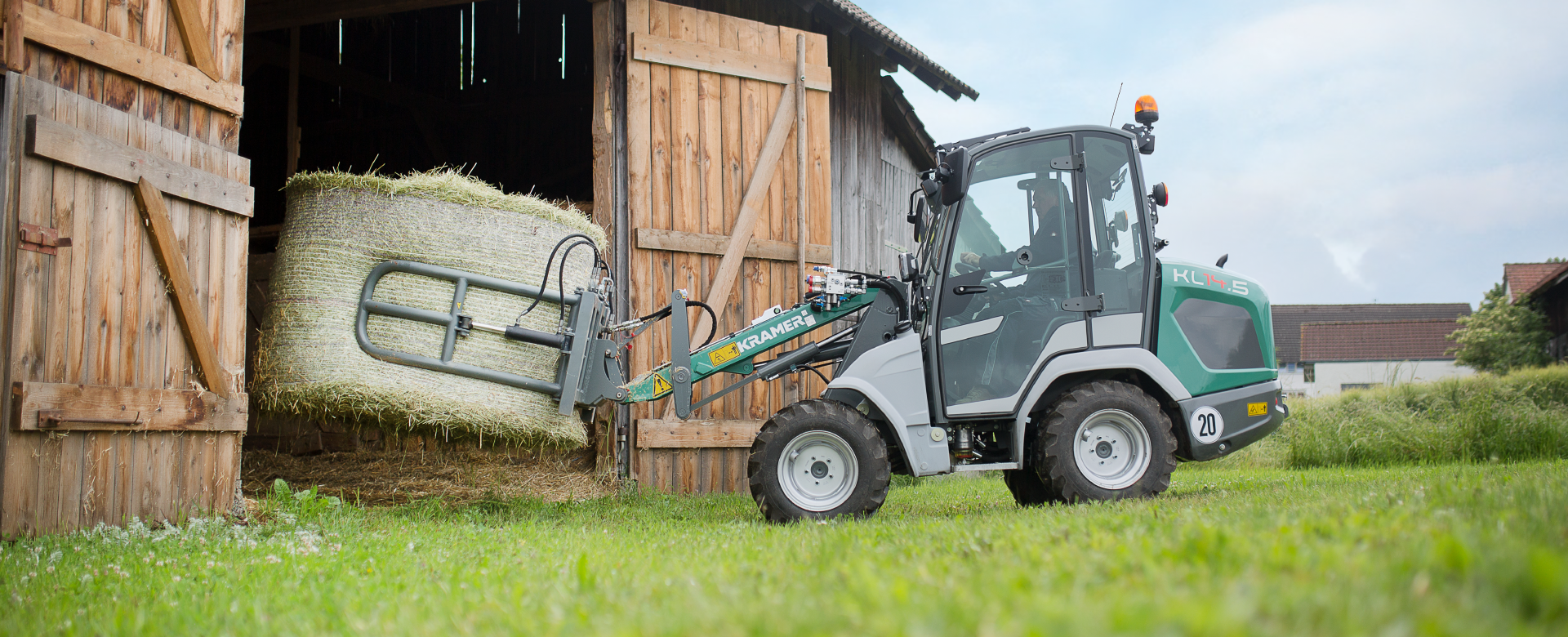 The compact KL14.5 while loading a straw bale through a stable gate.