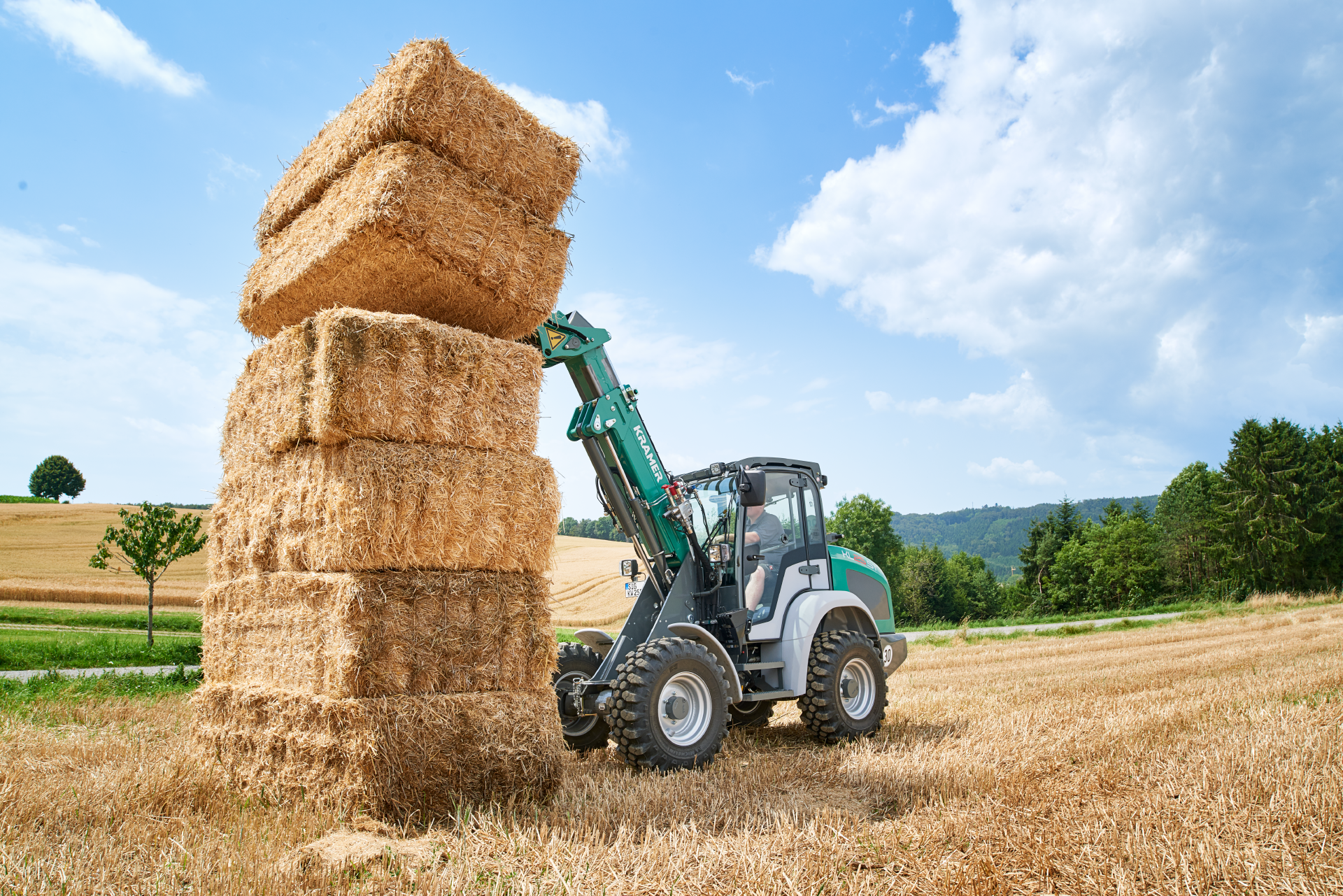 The Kramer telescopic wheel loader KL25.5T while stacking straw on a field.
